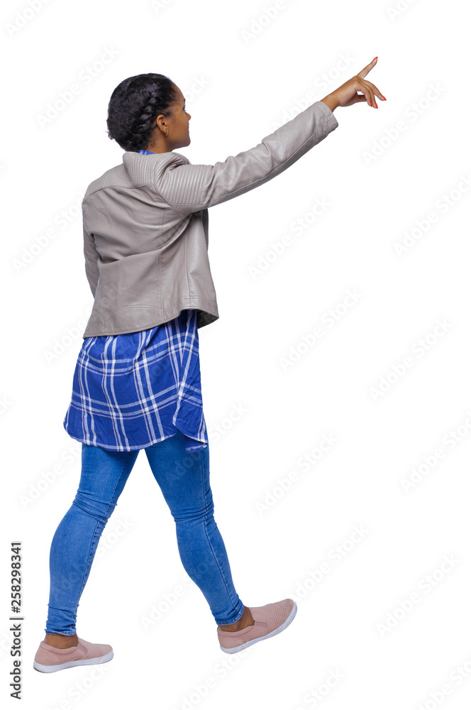 Side view of a young black girl in jeans and a checkered shirt.