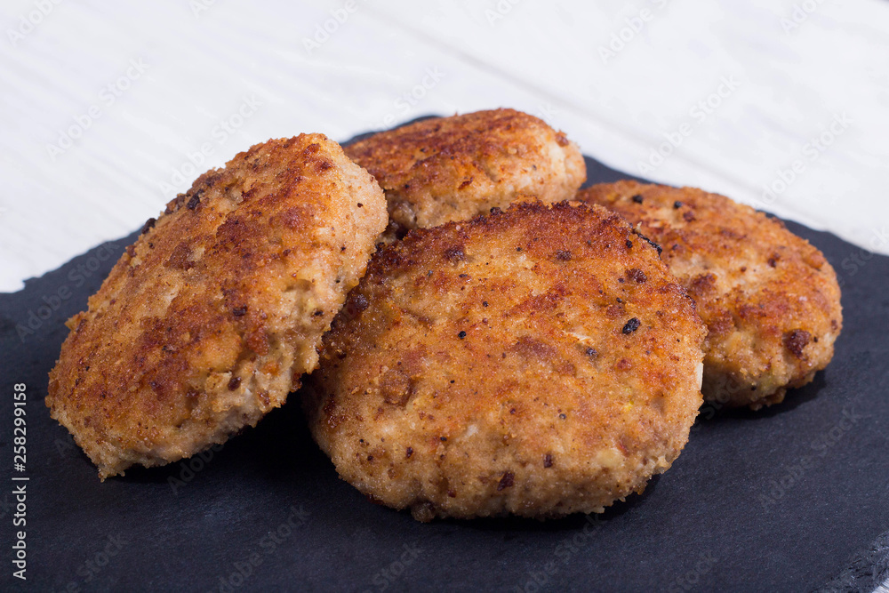 cutlets on a black flat plate, on a white wooden background cutlets on a black flat plate, on a white wooden background