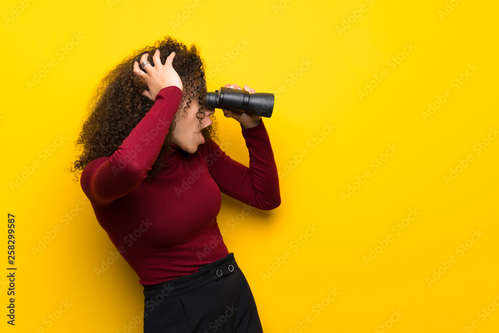 Dominican woman with turtleneck sweater and looking in the distance with binoculars Dominican woman with turtleneck sweater and looking in the distance with binoculars