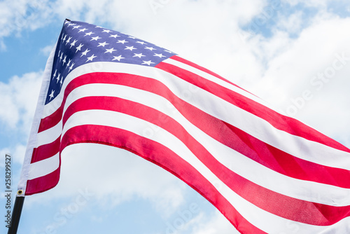 low angle view of american flag with stars and stripes against blue sky