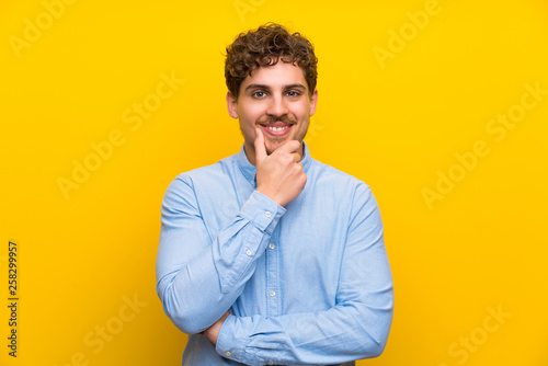 Blonde man over isolated yellow wall laughing