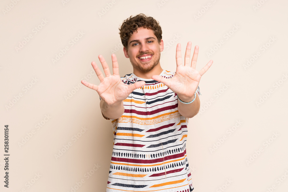 Blonde man over isolated wall counting ten with fingers