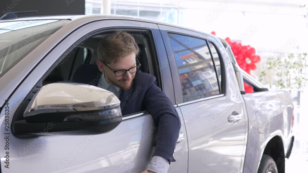 portrait of happy car buyer, smiling client man enjoy new automobile and shows keys sitting in cabin and looking through window at auto salon portrait of happy car buyer, smiling client man enjoy new automobile and shows keys sitting in cabin and looking through window at auto salon