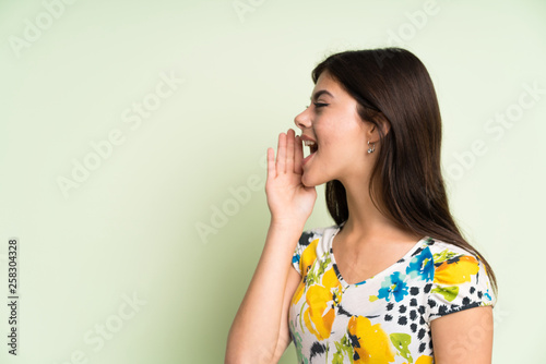 Teenager girl with floral dress shouting with mouth wide open