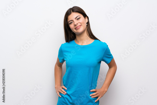 Teenager girl with blue shirt posing with arms at hip and smiling