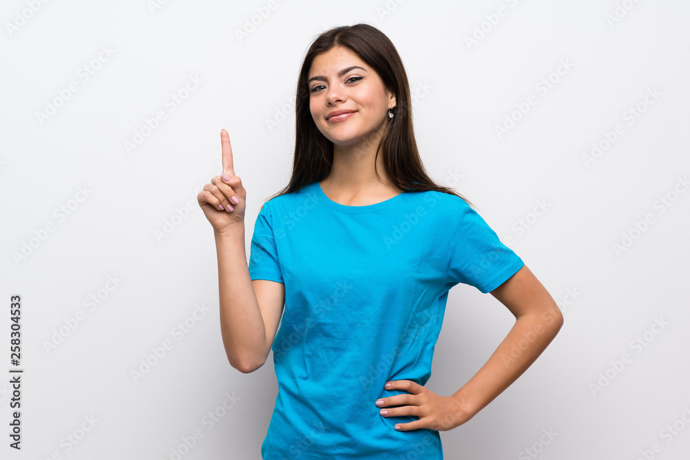 Teenager girl with blue shirt showing and lifting a finger in sign of the best Teenager girl with blue shirt showing and lifting a finger in sign of the best