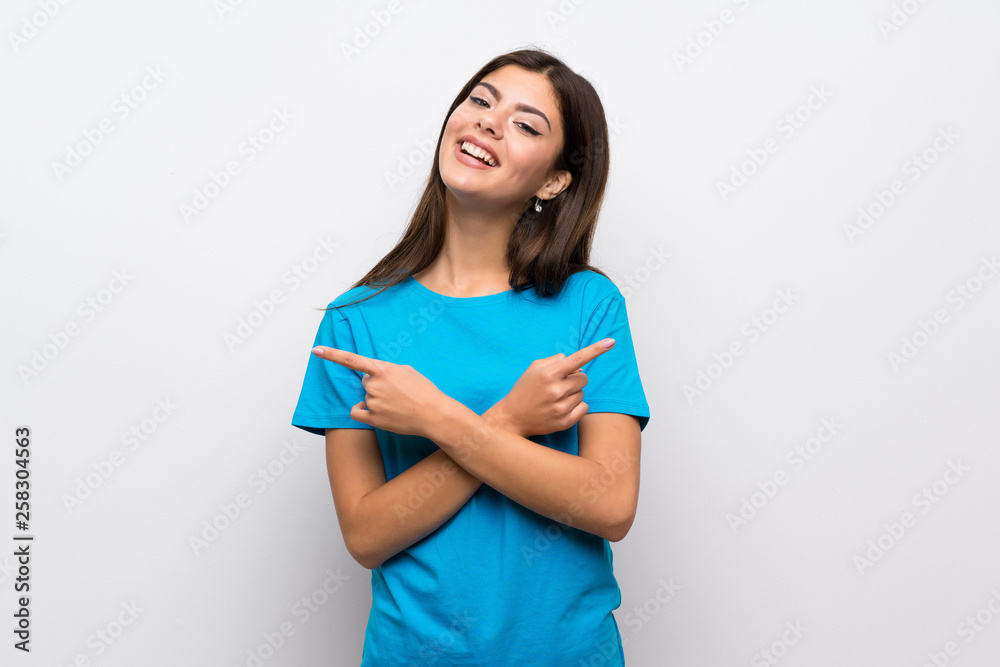 Teenager girl with blue shirt pointing to the laterals having doubts Teenager girl with blue shirt pointing to the laterals having doubts