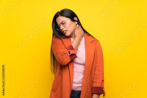 Young Colombian girl over yellow wall with neckache © luismolinero