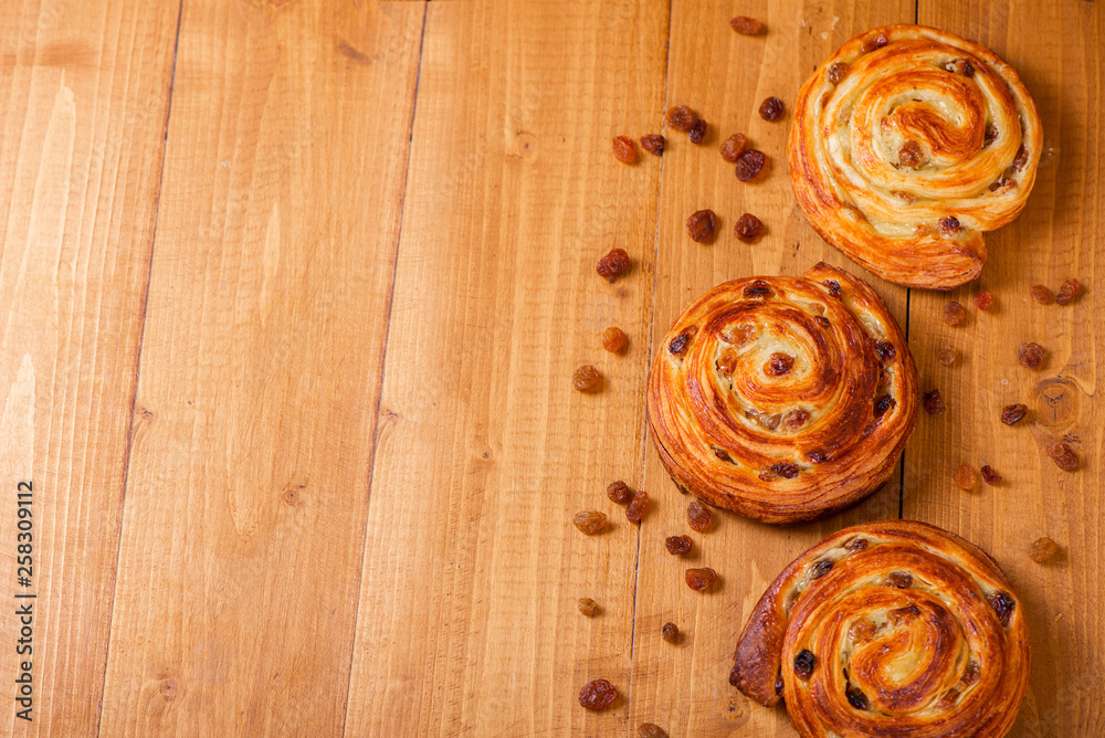 Fresh homemade pain au raisins croissant over wooden background Fresh homemade pain au raisins croissant over wooden background