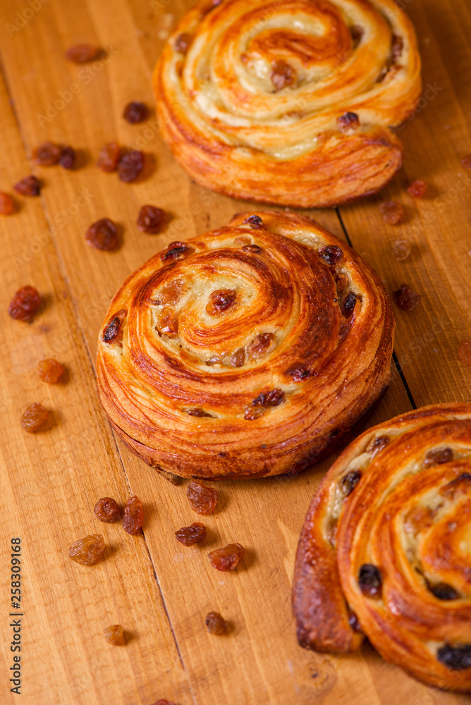 Fresh homemade pain au raisins croissant over wooden background Fresh homemade pain au raisins croissant over wooden background