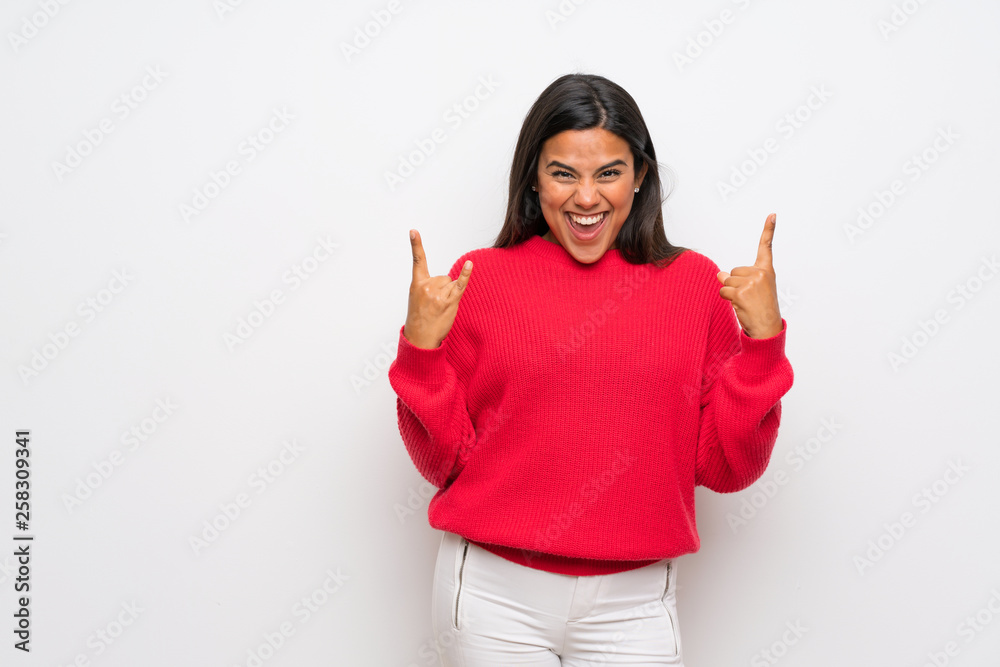 Young Colombian girl with red sweater making rock gesture Young Colombian girl with red sweater making rock gesture