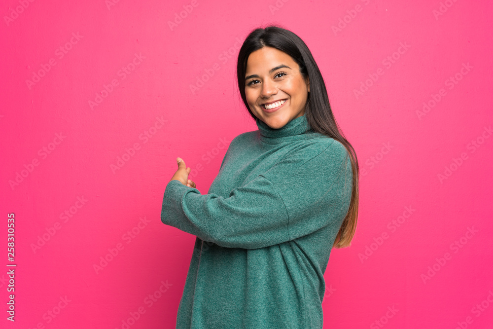Young Colombian girl with green sweater pointing back Young Colombian girl with green sweater pointing back