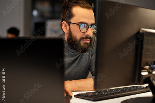 deadline, technology and people concept - close up of creative man in glasses working at night office and thinking