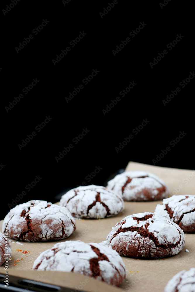 Chocolate cookies with cracks on baking paper and iolated on black. Cracked chocolate biscuits Chocolate cookies with cracks on baking paper and iolated on black. Cracked chocolate biscuits