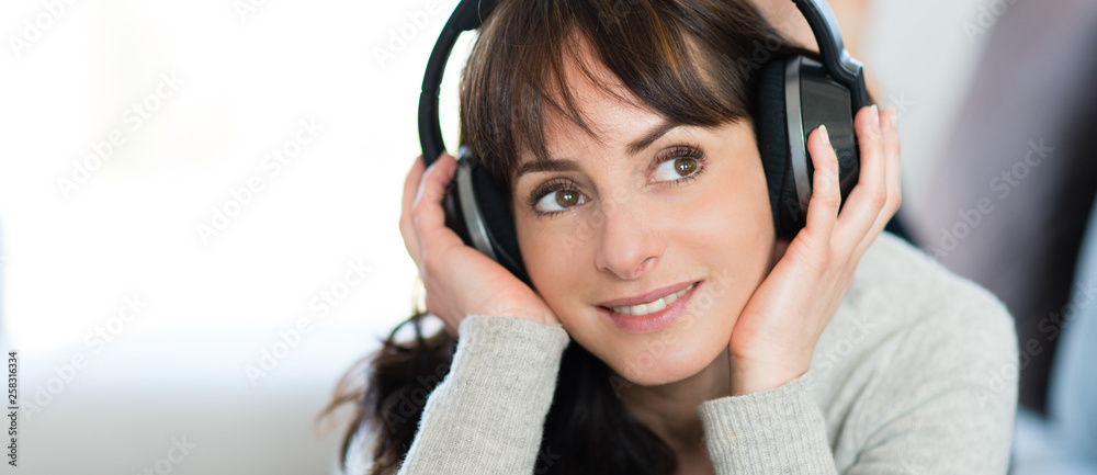 Jeune femme écoutant de la musique avec un casque audio - obrazy, fototapety, plakaty 
