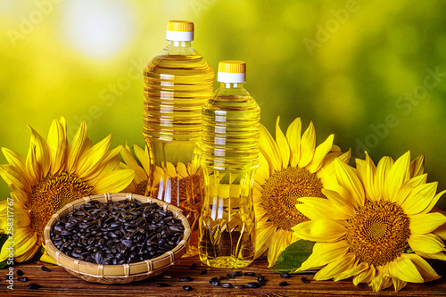 Rural still-life - sunflower oil in bottles with flowers of sunflower (Helianthus annuus), closeup
