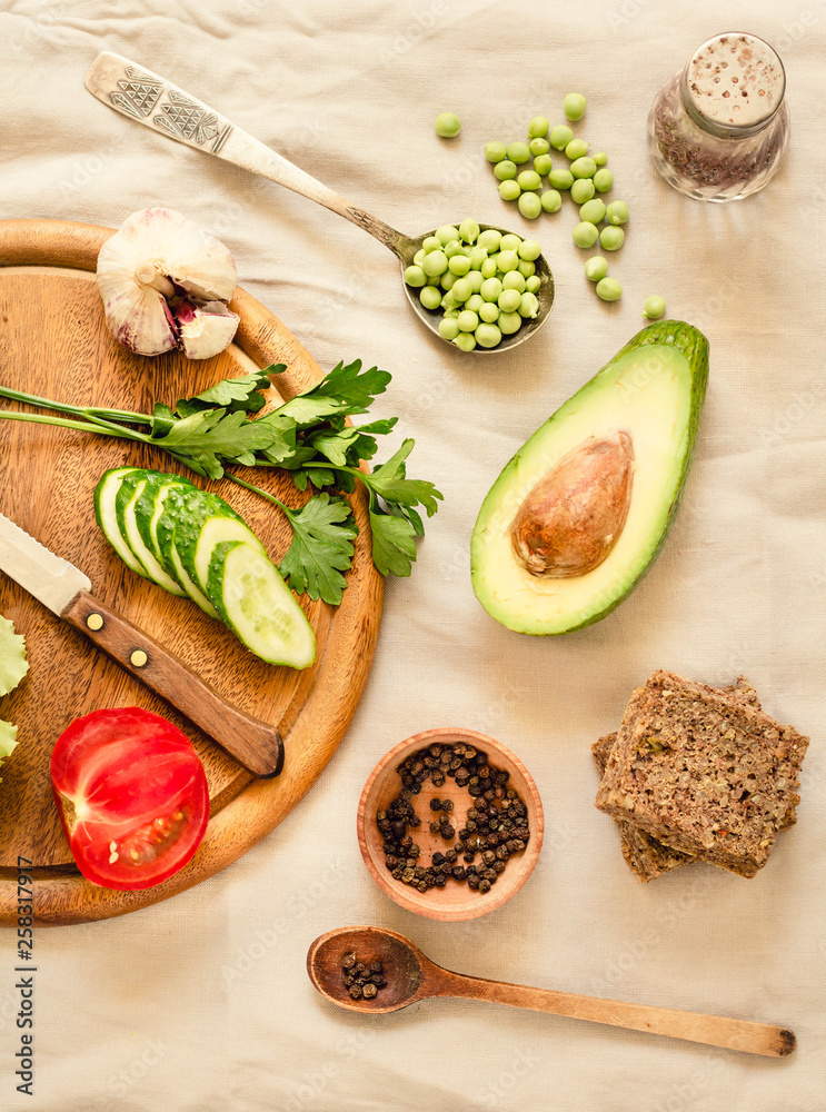 Ingredients for green salad with a piece of bread. Make a fresh salad of avocado, greens, peas, parsley, cabbage, cucumber and apples.Vegetables on a wooden board. Top view. Ingredients for green salad with a piece of bread. Make a fresh salad of avocado, greens, peas, parsley, cabbage, cucumber and apples.Vegetables on a wooden board. Top view.