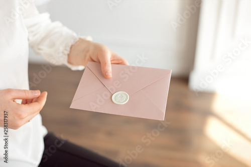 Close-up of woman in white shirt of business style holds in her hand a invitation card, card, letter