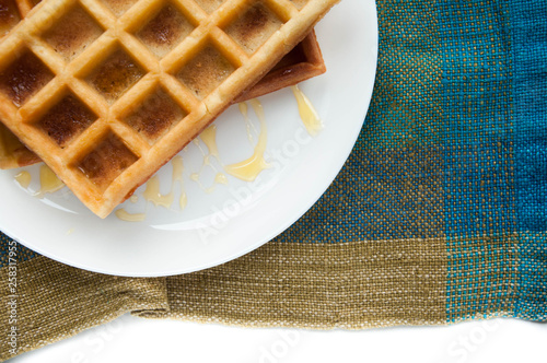 Belgian waffles on a white plate on the table. French or American breakfast. Vintage style. Sweet food.