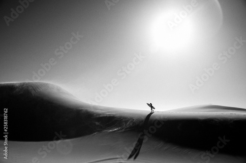 Frau mit Surfboard auf Düne photo