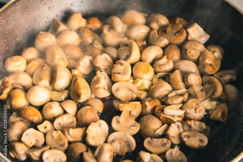 Champignon mushrooms are fried in a pan - close-up Champignon mushrooms are fried in a pan - close-up