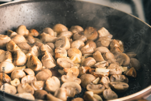 Champignon mushrooms are fried in a pan - close-up