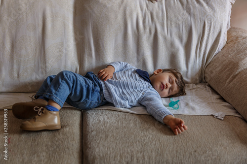Beautiful boy is sleeping peacefully on the sofa in the living room of his house © Óscar