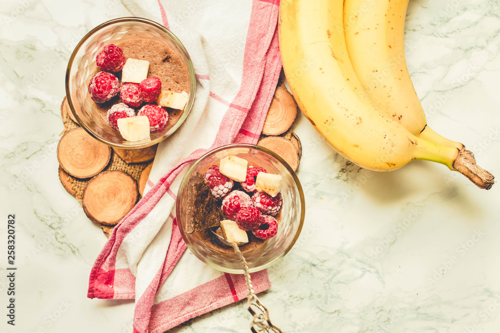 Chocolate avocado mousse (soufflé) from aquafaba. Vegan dessert in jars on a white marble background.Tone. Chocolate avocado mousse (soufflé) from aquafaba. Vegan dessert in jars on a white marble background.Tone.