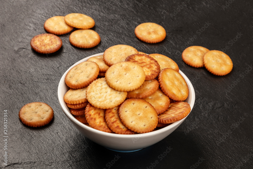 A photo of salt crackers in a bowl on a dark background with copy space A photo of salt crackers in a bowl on a dark background with copy space