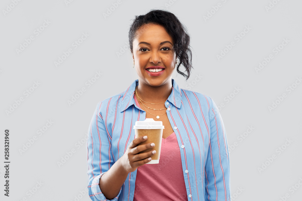 people and drinks concept - happy african american young woman drinking takeaway coffee from paper cup over grey background people and drinks concept - happy african american young woman drinking takeaway coffee from paper cup over grey background