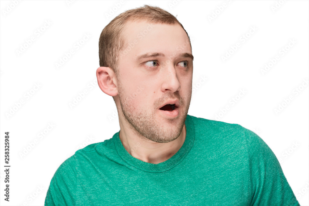 Fototapeta premium A funny young man in a green shirt shows disappointment