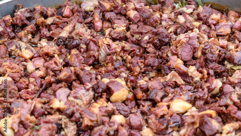 Large group of pieces of different cubes of fried meat in soft focus, at a street food market 