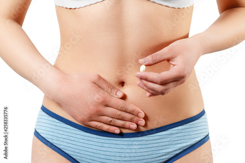 Woman holding white pill against her nude body. Diet supplement concept On white