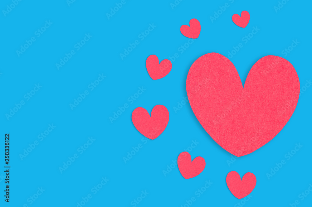 One big red paper heart and scattered small hearts in center of blue table. Top view. Valentines Day concept. Copy space for your text