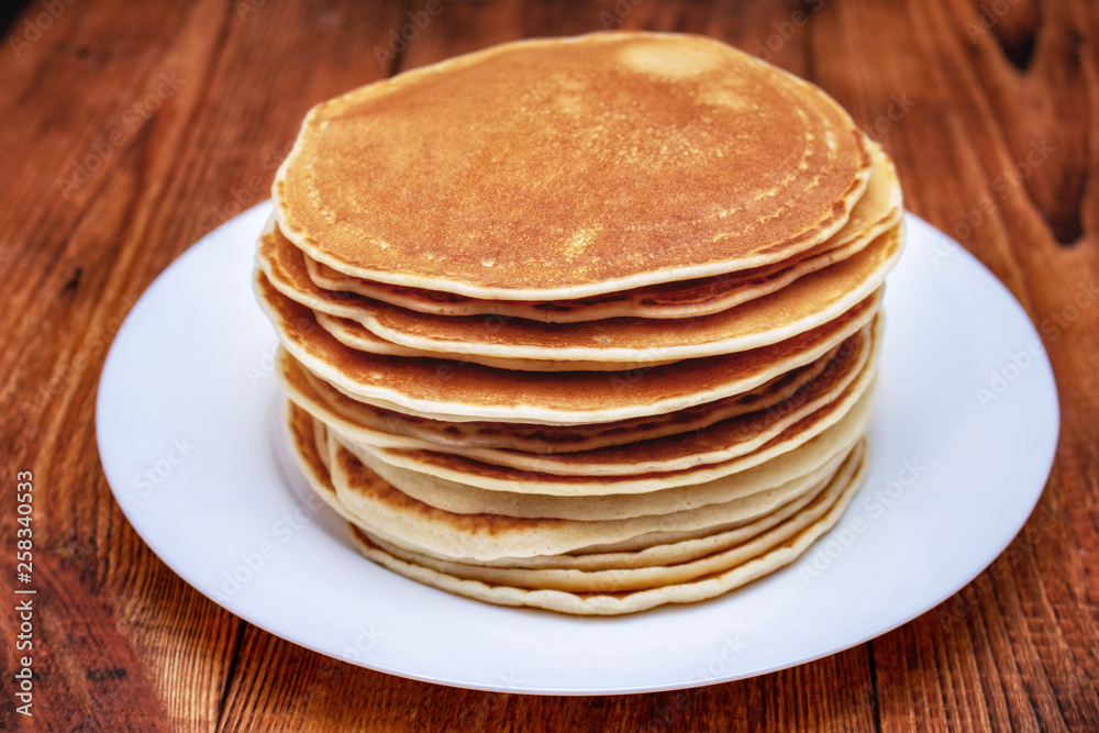 stack of pancakes on a white plate on a dark brown background