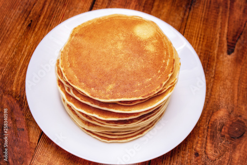 stack of pancakes on a white plate on a dark brown background