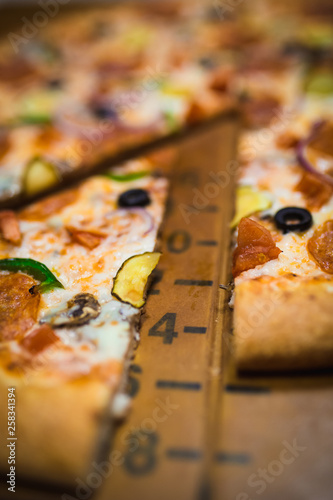 A slice of pizza close-up, appetizing pizza filling, cheese. Hand takes a separate piece of pizza