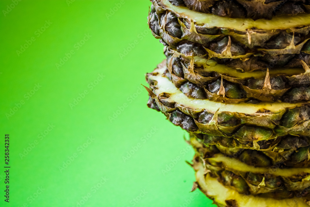 The fresh pineapple cut on round pieces. Tropical, exotic fruit on a green background. Summer. Bright colors. The fresh pineapple cut on round pieces. Tropical, exotic fruit on a green background. Summer. Bright colors.
