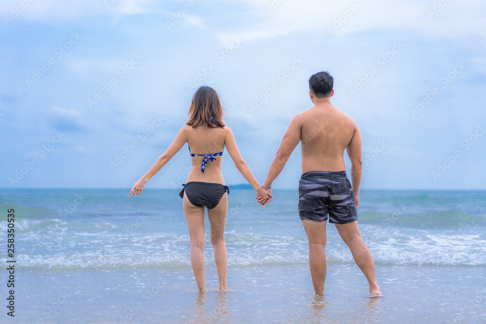Young Asian honeymoon couple in holiday beach and walking on beach,They wear bikini and have a happy holiday. Young Asian honeymoon couple in holiday beach and walking on beach,They wear bikini and have a happy holiday.