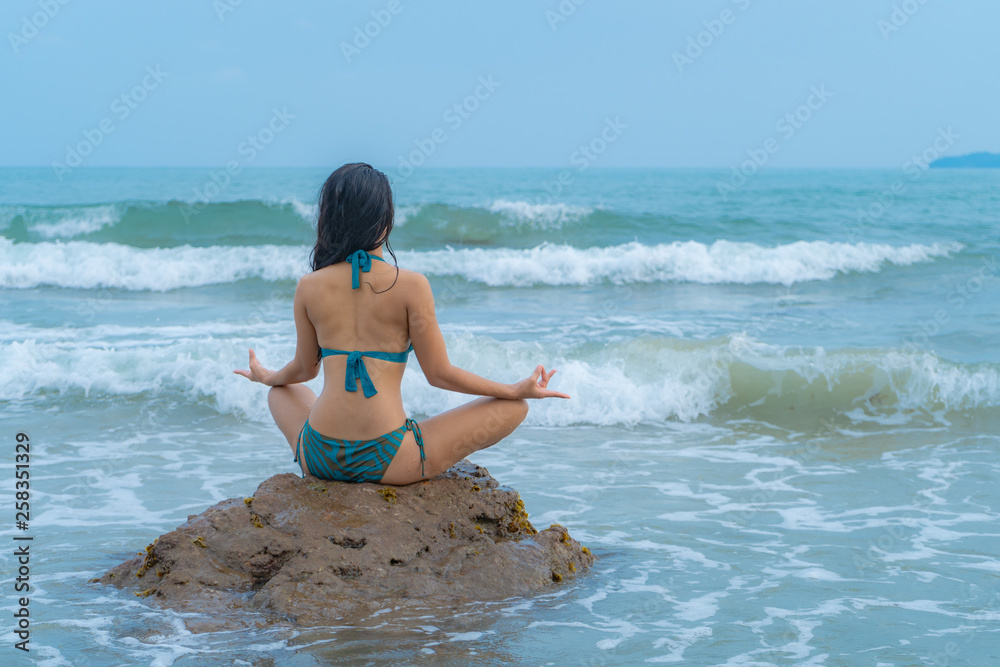 Asian woman practicing yoga on rocks in the sea and balancing training and the action or practice of meditating. Asian woman practicing yoga on rocks in the sea and balancing training and the action or practice of meditating.