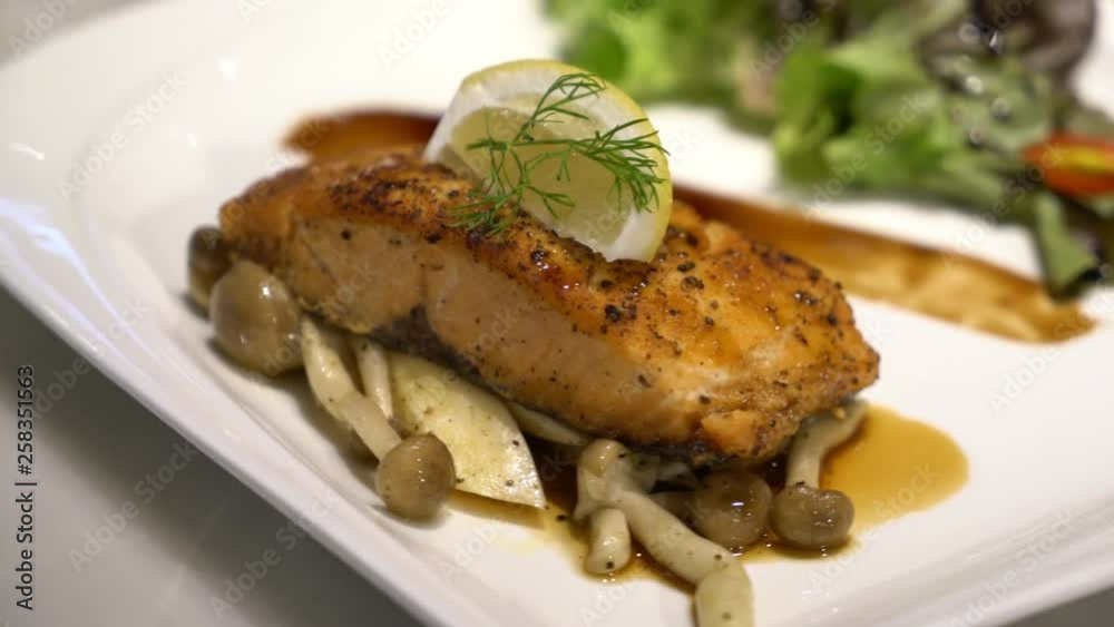 A gourmet grilled salmon fillet steak served with mushrooms and salad A gourmet grilled salmon fillet steak served with mushrooms and salad
