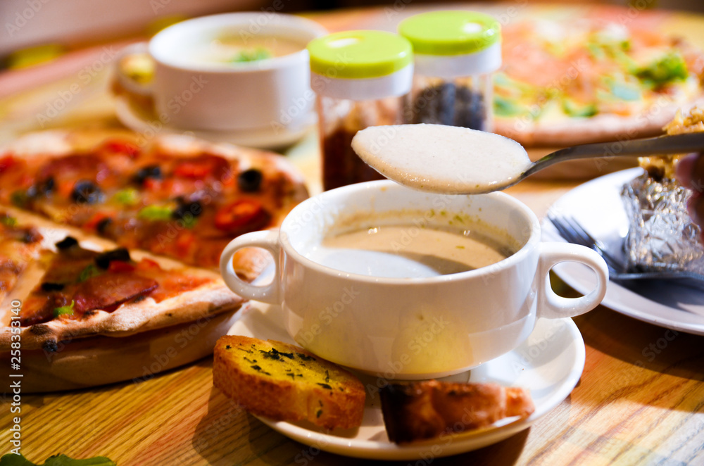 Bowl on a table with mushroom soup and a spoon hovering above Bowl on a table with mushroom soup and a spoon hovering above