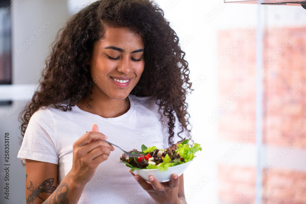 cheerful young afro american woman eating vegetable salad in home kitchen cheerful young afro american woman eating vegetable salad in home kitchen