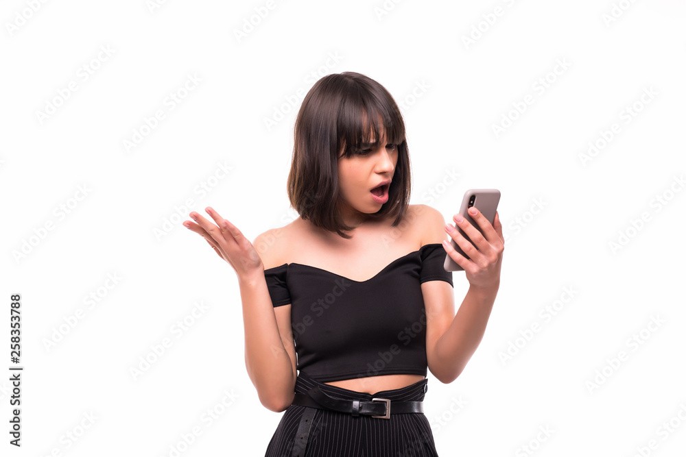 Annoyed angry young woman mad about spam message stuck phone looking at smartphone isolated on white background. Furious teen girl having problem with cellphone irritated by broken mobile Annoyed angry young woman mad about spam message stuck phone looking at smartphone isolated on white background. Furious teen girl having problem with cellphone irritated by broken mobile