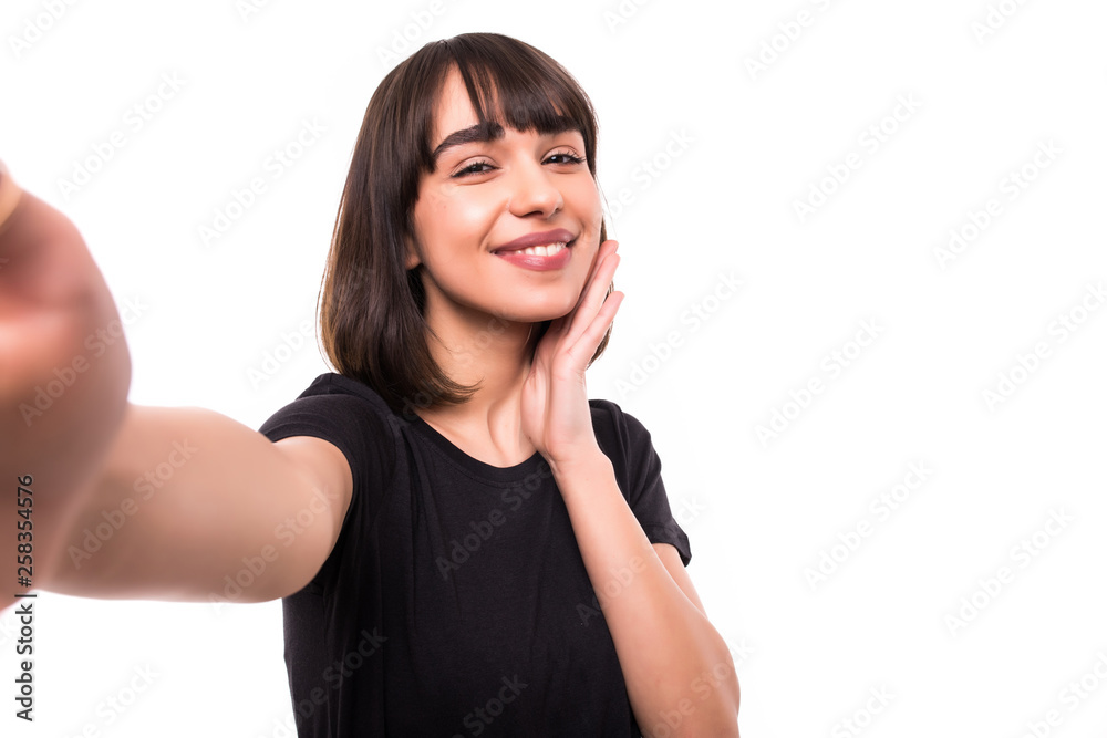 Portrait of a smiling cute woman making selfie photo on smartphone on a white background Portrait of a smiling cute woman making selfie photo on smartphone on a white background