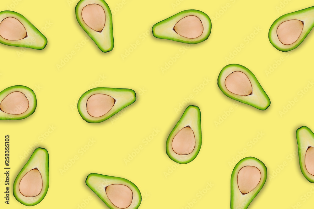Lots of scattered tasty fresh halves of organic avocado with kernels on yellow table in kitchen or market. Top view. Cooking concept Lots of scattered tasty fresh halves of organic avocado with kernels on yellow table in kitchen or market. Top view. Cooking concept