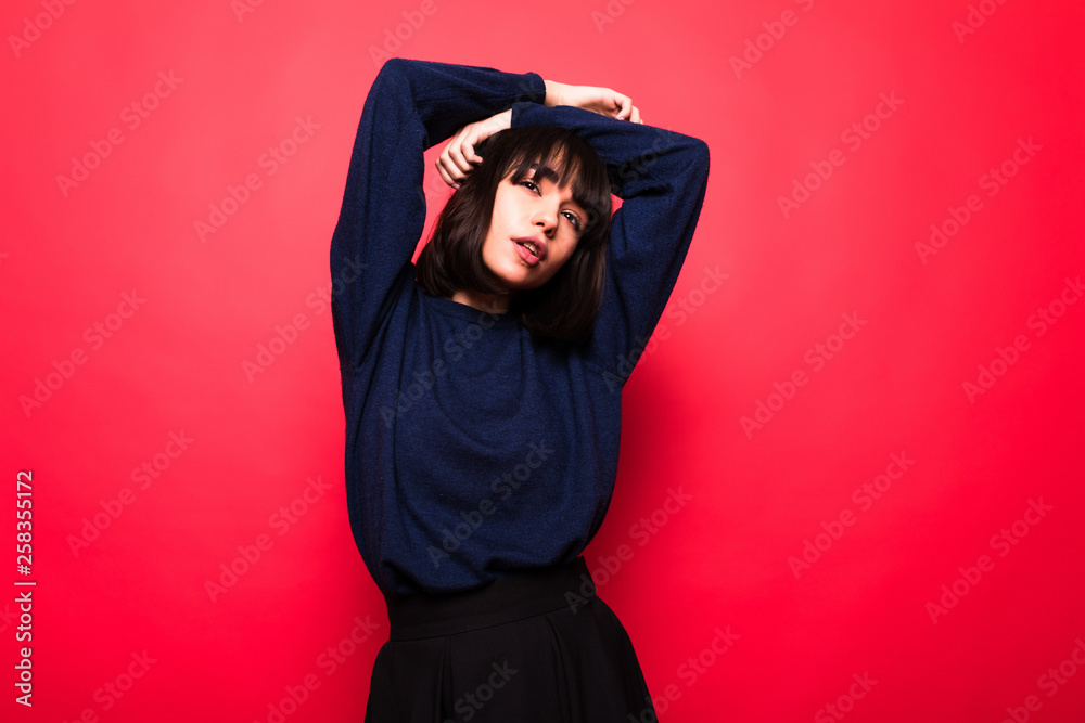 Positive attractive woman wears casual sweater,isolated against red background Positive attractive woman wears casual sweater,isolated against red background