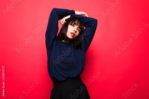 Positive attractive woman wears casual sweater,isolated against red background © F8  \ Suport Ukraine