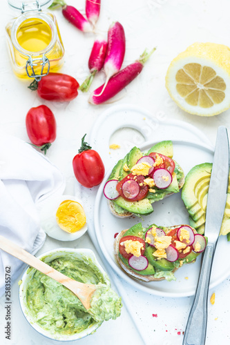 Breakfast: avocado toasts with ingredients tomato, radish, lemon andolive oil. Top view. © Irina