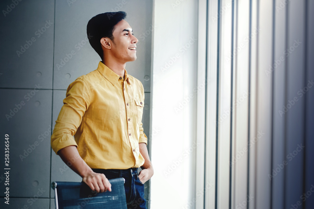 Portrait of Happy Businessman Standing by the Window in Office. Looking Away and Smiling. Dreaming for Success Portrait of Happy Businessman Standing by the Window in Office. Looking Away and Smiling. Dreaming for Success